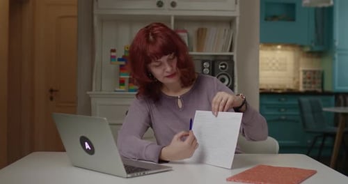 40s Female Teacher Talking To Laptop and Holding Sheet of Paper with Medical Graph