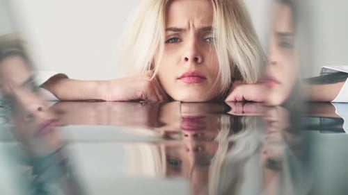 Thoughtful Young Woman Resting Head on Reflective Table