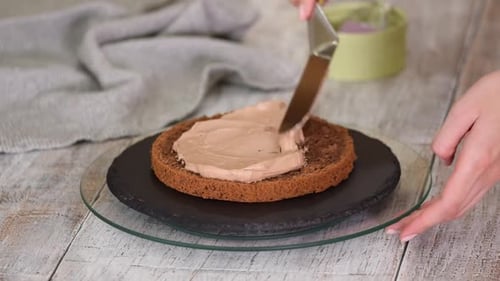 Chocolate Cake Being Frosted with Brown Cream