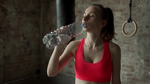 Woman Drinking Water in Gym After Workout