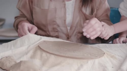 Adult and Child Flattening Clay Together