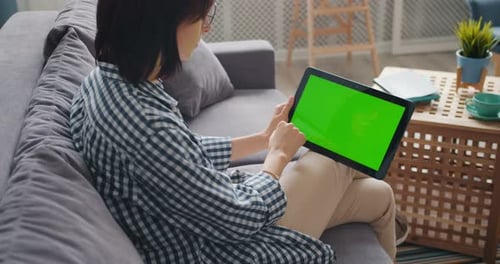 Young Lady Touching Green Screen of Modern Tablet Using Gadget in Apartment