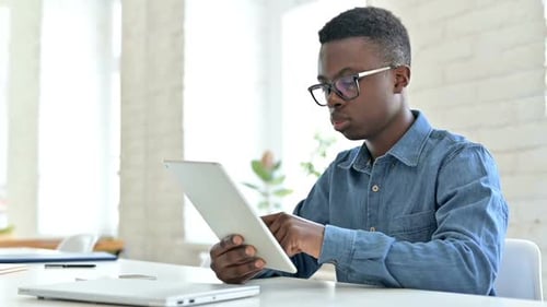 Young Adult Using Tablet in Bright Office