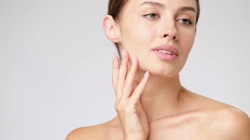 Young Woman Gently Touches Face in Close Up