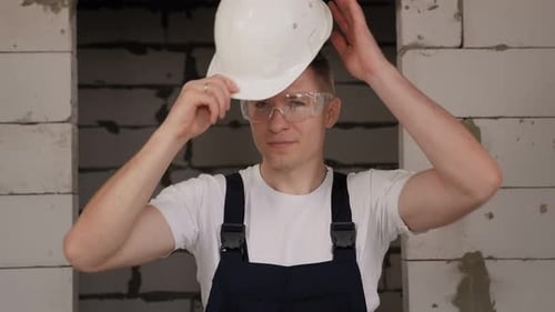 Un ouvrier met un casque de chantier blanc sur un chantier