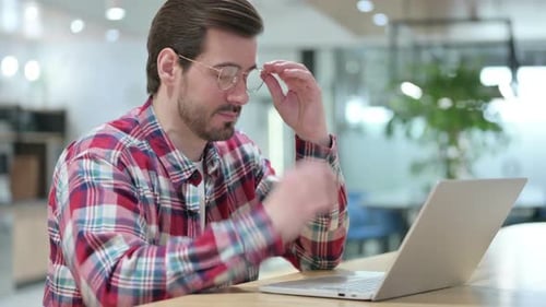 Tired Man Working at Laptop in Office