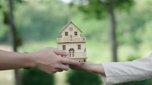 Model House Exchanged Between Hands in a Natural Setting