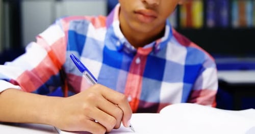 Boy Writing in Notebook at School