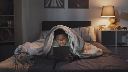 Garçon utilisant la tablette dans son lit
