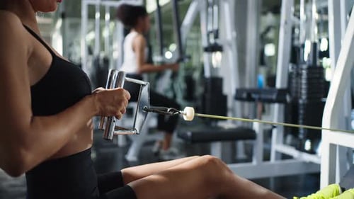 4K Confidence Latin woman in sportswear pulling weight lifting machine at gym.