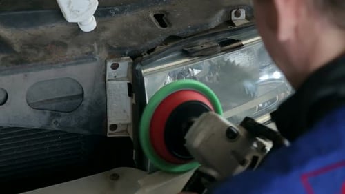 Primer plano de un mecánico pule el faro con una rectificadora