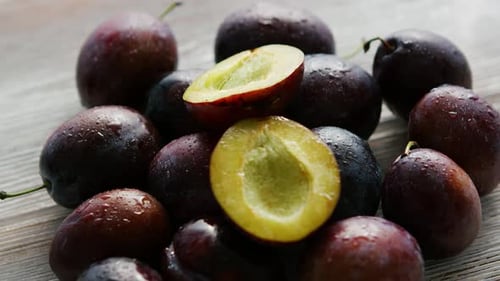 Pile of Plums with Cut Half on Wood