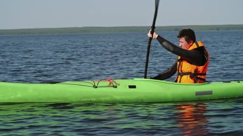 Man Paddles Kayak Across Calm Water