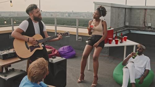 Man Playing Song to Friends on Rooftop Terrace