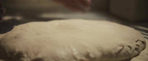 Hands Dusting Flour on Dough in Kitchen