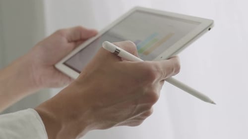 Empresário asiático de perto usando tablet examinando relatórios financeiros.
