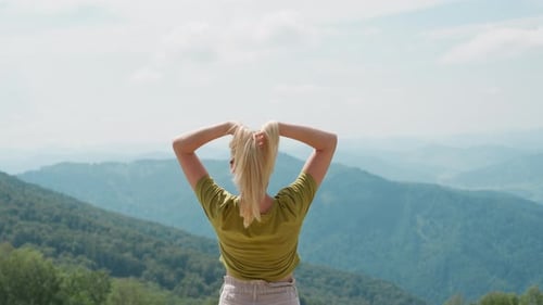 Elegant Woman Lifts Up Hair at Picturesque Mountain Valley