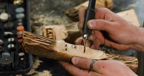 Close up male hands using power wood working tools graver