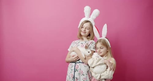 Nette Mädchen mit Hasenohren, die mit dem Kaninchen auf isoliertem Hintergrund spielen