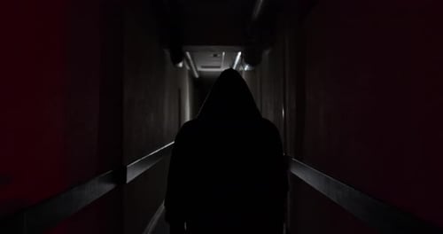 A boxer in a hood walks along a dark corridor to a fight in slow motion