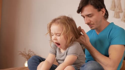 Father Gently Brushing Child's Hair at Home