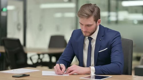 Homme d'affaires pensif écrivant sur le papier et pensant