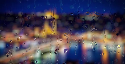 Rain Drops on Window Glass with Blurred City Night Lights