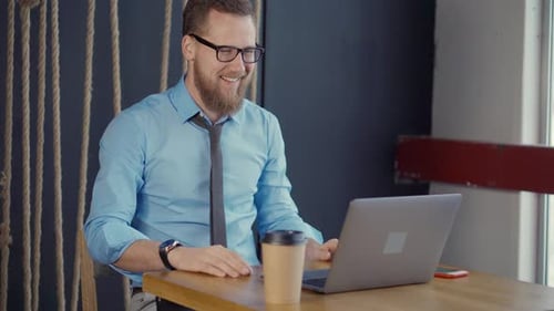 Young Adult Works, Answers Cell Phone at Laptop