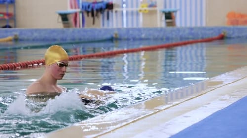 Swimming Instructor Provides Support to a Person Underwater in the Pool