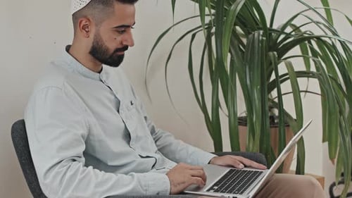 Man Using Laptop Sitting in Chair Indoors