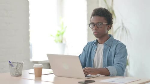 Thumbs Down By Young African Man Using Laptop in Office