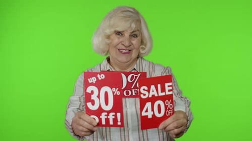 Smiling Senior Woman Holding Sale Signs on Green Screen