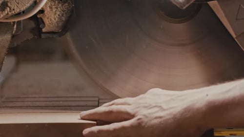 Carpentry Works Worker Slowly Cutting Along the Wooden Detail with a Big Circular Saw in Small