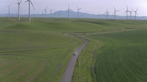 Car Driving On The Dirt Road Among Windmills