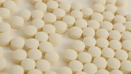 Close-Up of White Pills Scattered on a White Surface