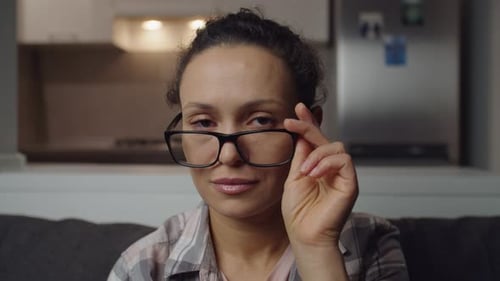 Woman Adjusts Glasses Looking Directly at Camera