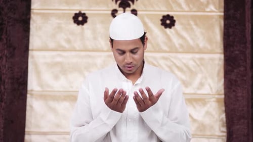 Young Man Praying Faithfully in White Tunic and Cap