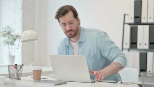 Man Working at Desk on Laptop in Modern Office