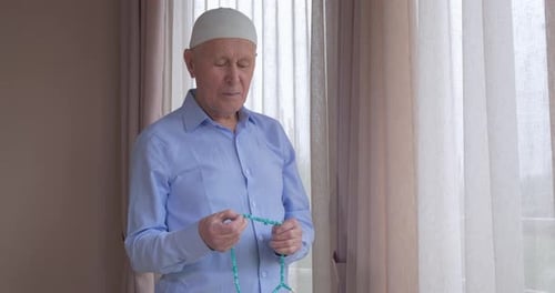 Ein alter Mann mit Rosenkranzperlen betet