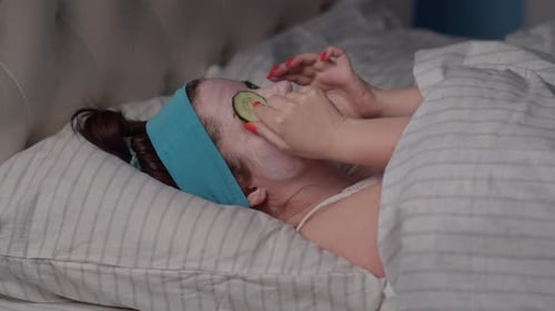 Woman Applies Cucumber Slices to her Face
