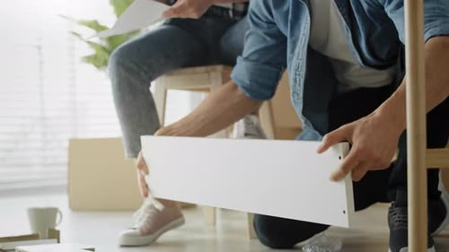 Tracking video of couple checking manual before installing furniture