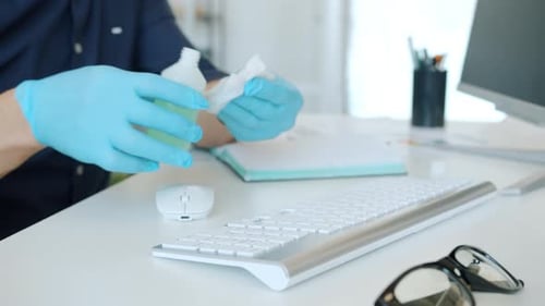 Close-up of Guy's Hands Wet Wiping Computer Keyboard at Work Using Sanitizer