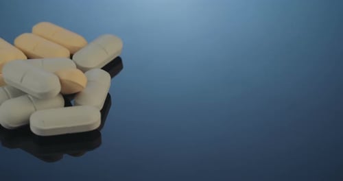 Pile of White and Beige Pills on Reflective Surface