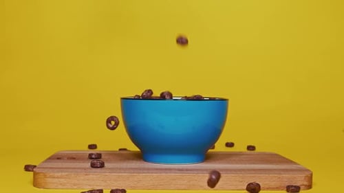 Cereal Rings Falling Into Blue Bowl on Yellow