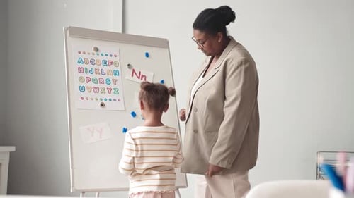 Teacher and Child Learning Alphabet at White Board