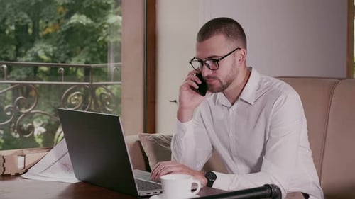 Businessman Talking on the Phone in a Cafe