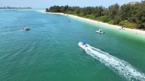 Flying over a secluded beach with boats moving and boats beached.