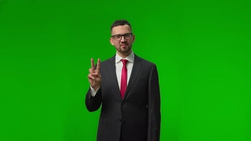 Portrait of Successful Young Businessman Showing Victory Sign on Isolated Green Background