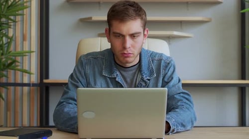 Young Adult Works at Laptop in Office