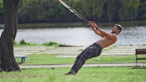 Man Exercises with Suspension Straps in Urban Park